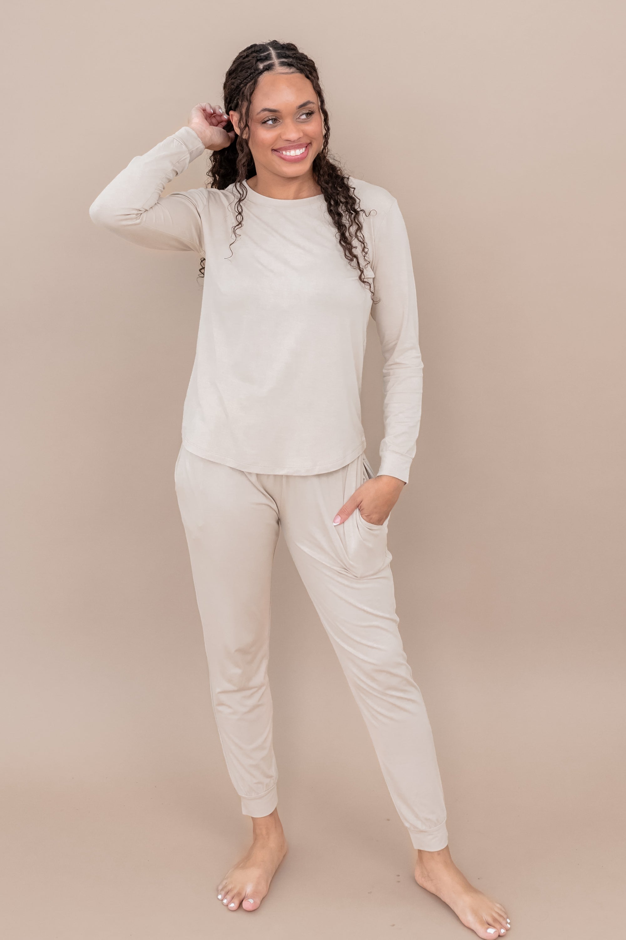 Woman wearing a beige long-sleeve top and pants against a beige background