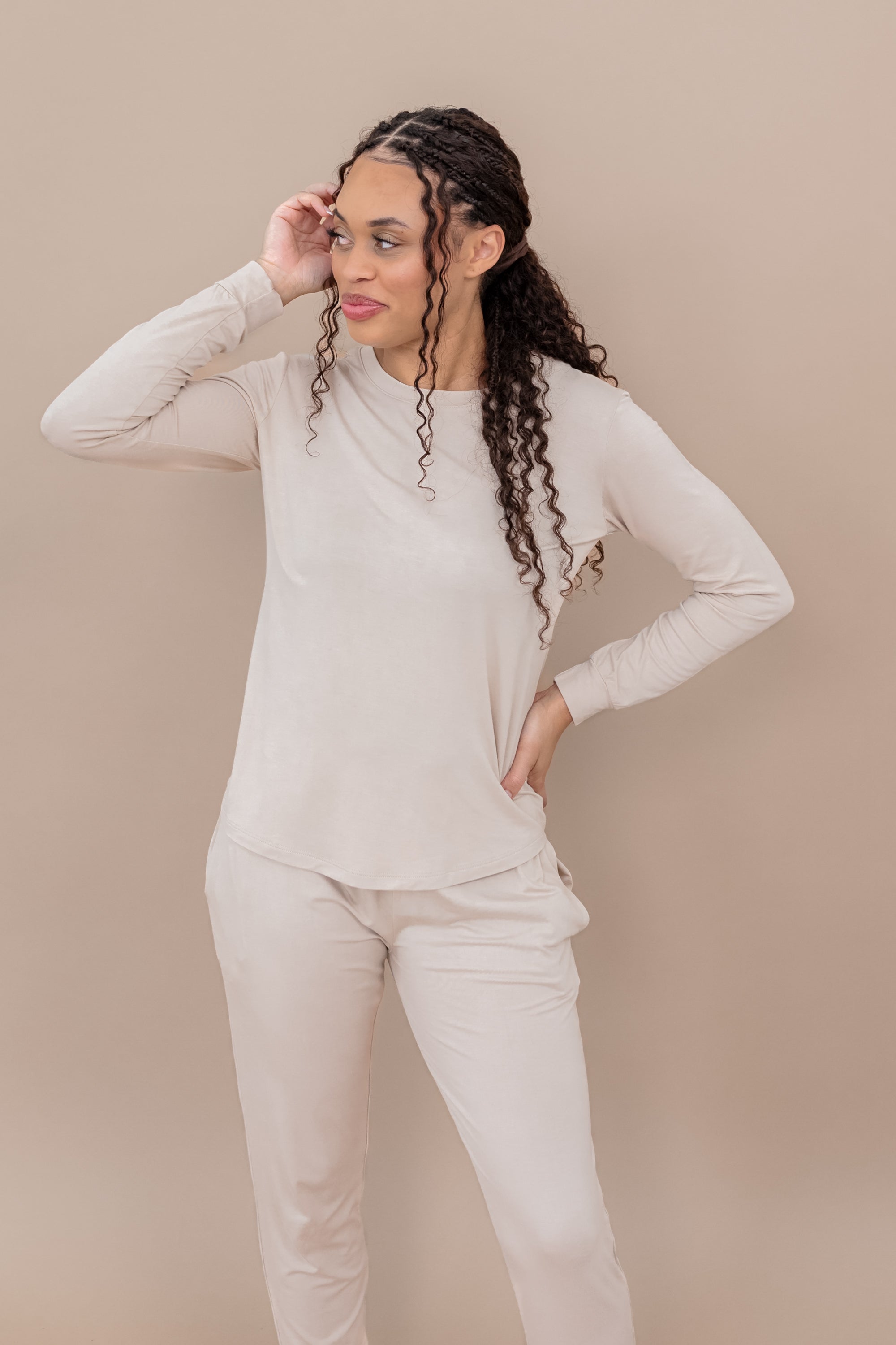 Woman wearing a beige long-sleeve lounge top and pants against a beige background