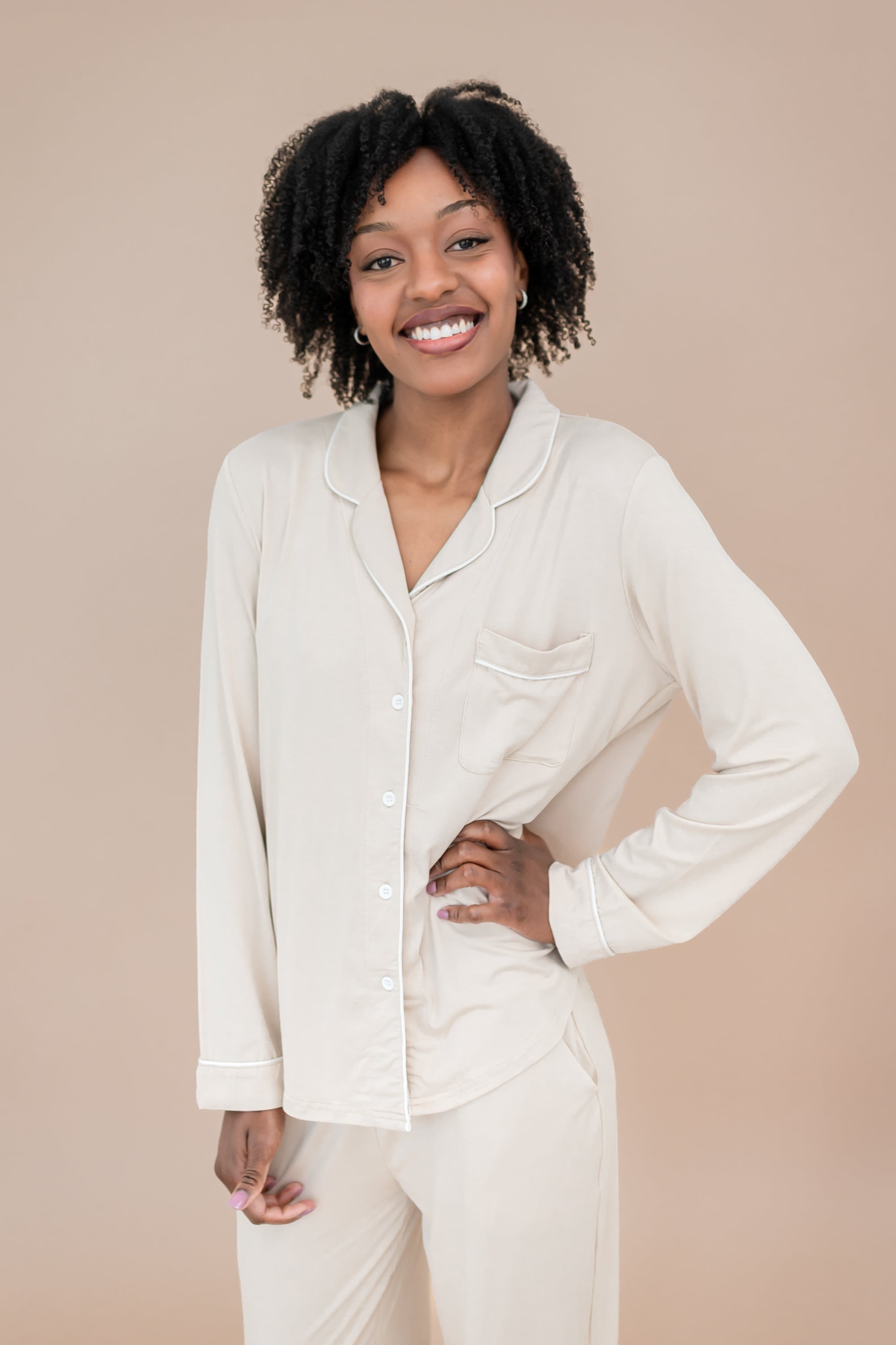 Woman wearing a bisque pajama set with hand on hip against a beige background