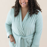 Model wearing the Adult Robe in Sage with one hand in robe pocket and the other hand on her thigh