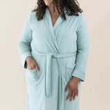Smiling model wearing Kyte Baby's Adult Robe in Sage