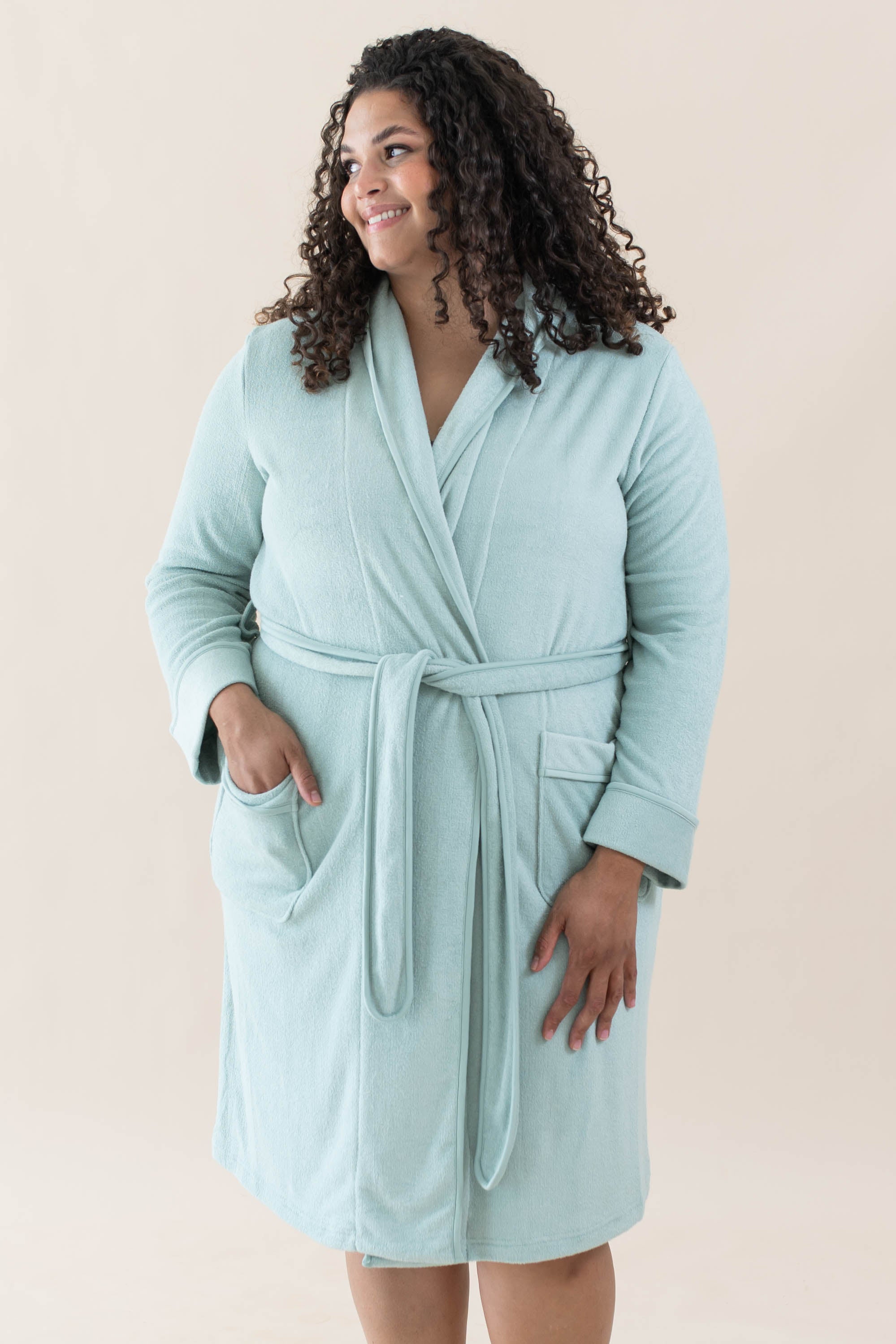 Smiling model wearing Kyte Baby's Adult Robe in Sage