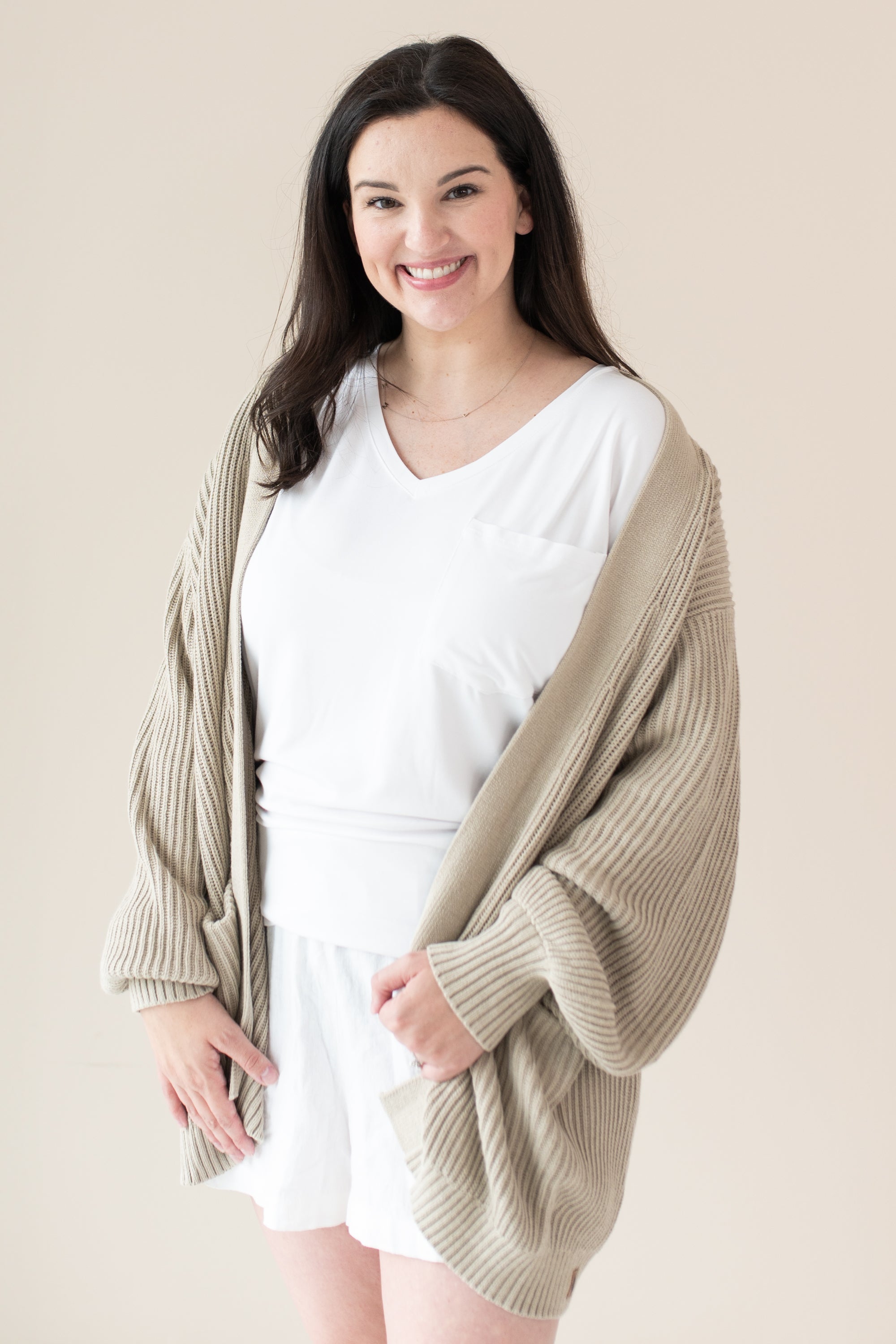 Woman in white outfit modeling Chunky Knit Women's Oversized Cardigan in Almond
