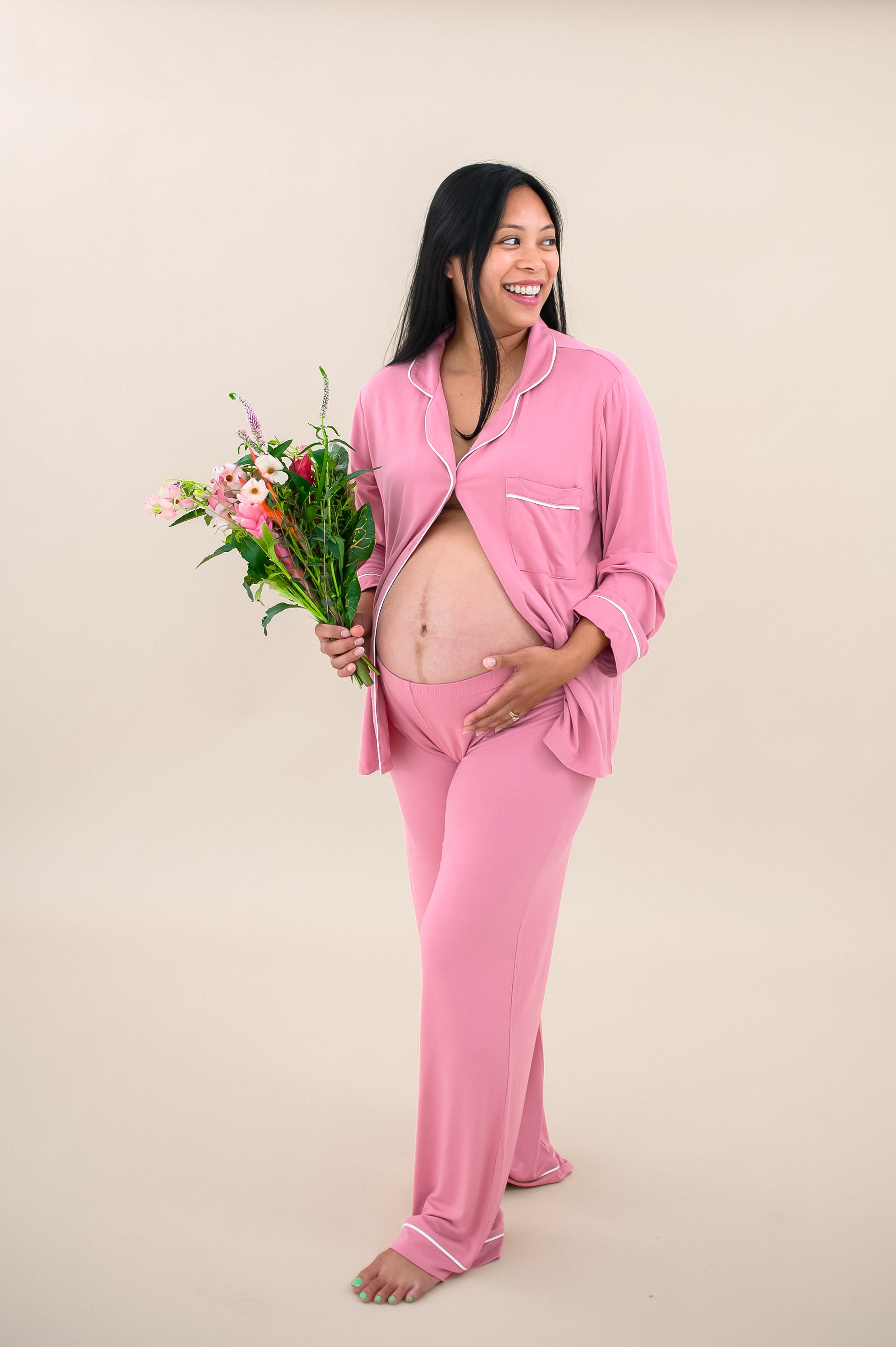 Model wearing Women's Long Sleeve Pajama Set in Apple Blossom with Cloud Trim with some buttons undone to show baby bump