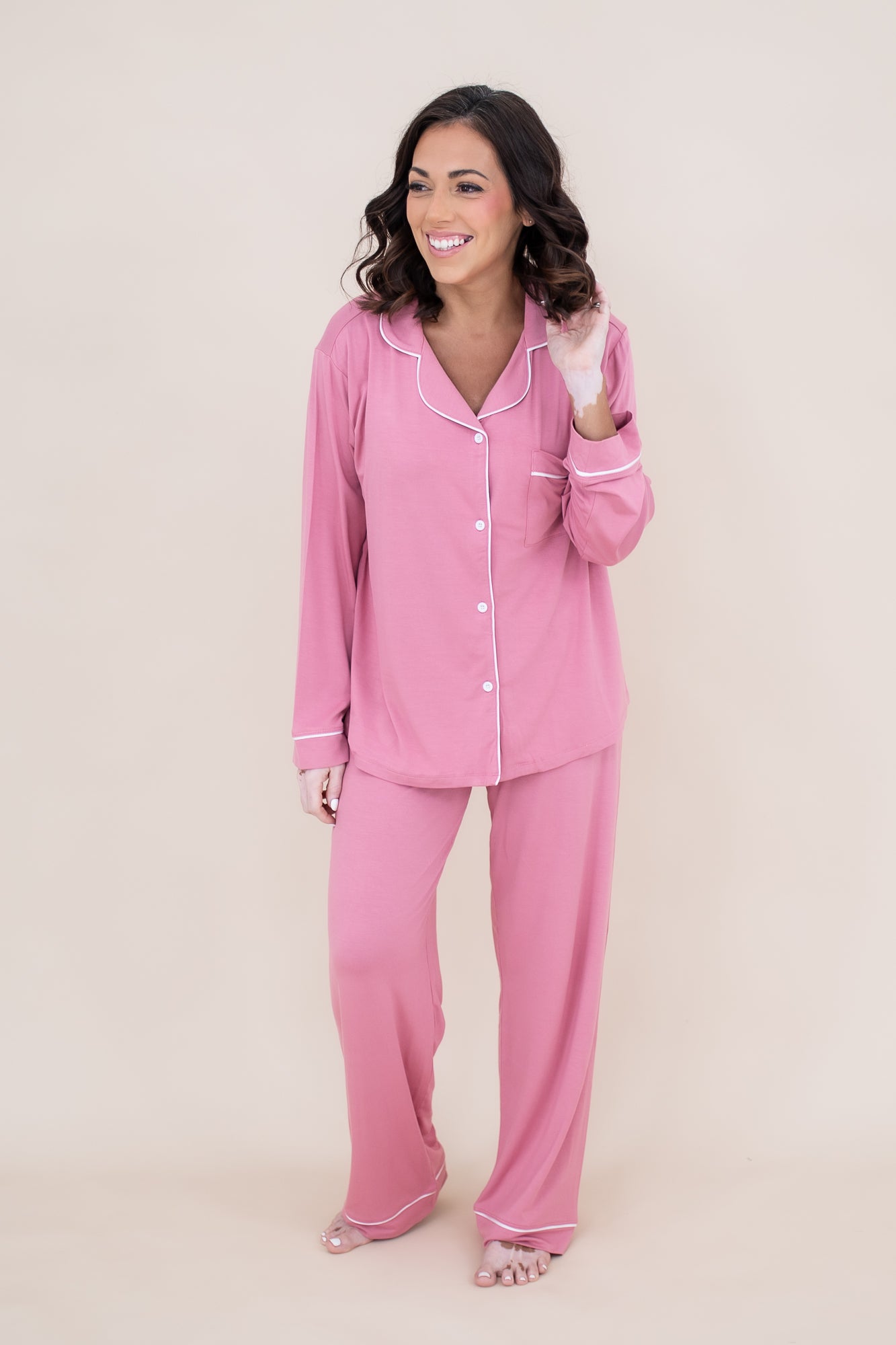 Woman smiling to the side while modeling the Kyte Women's Long Sleeve Pajama Set in Apple Blossom with Cloud Trim
