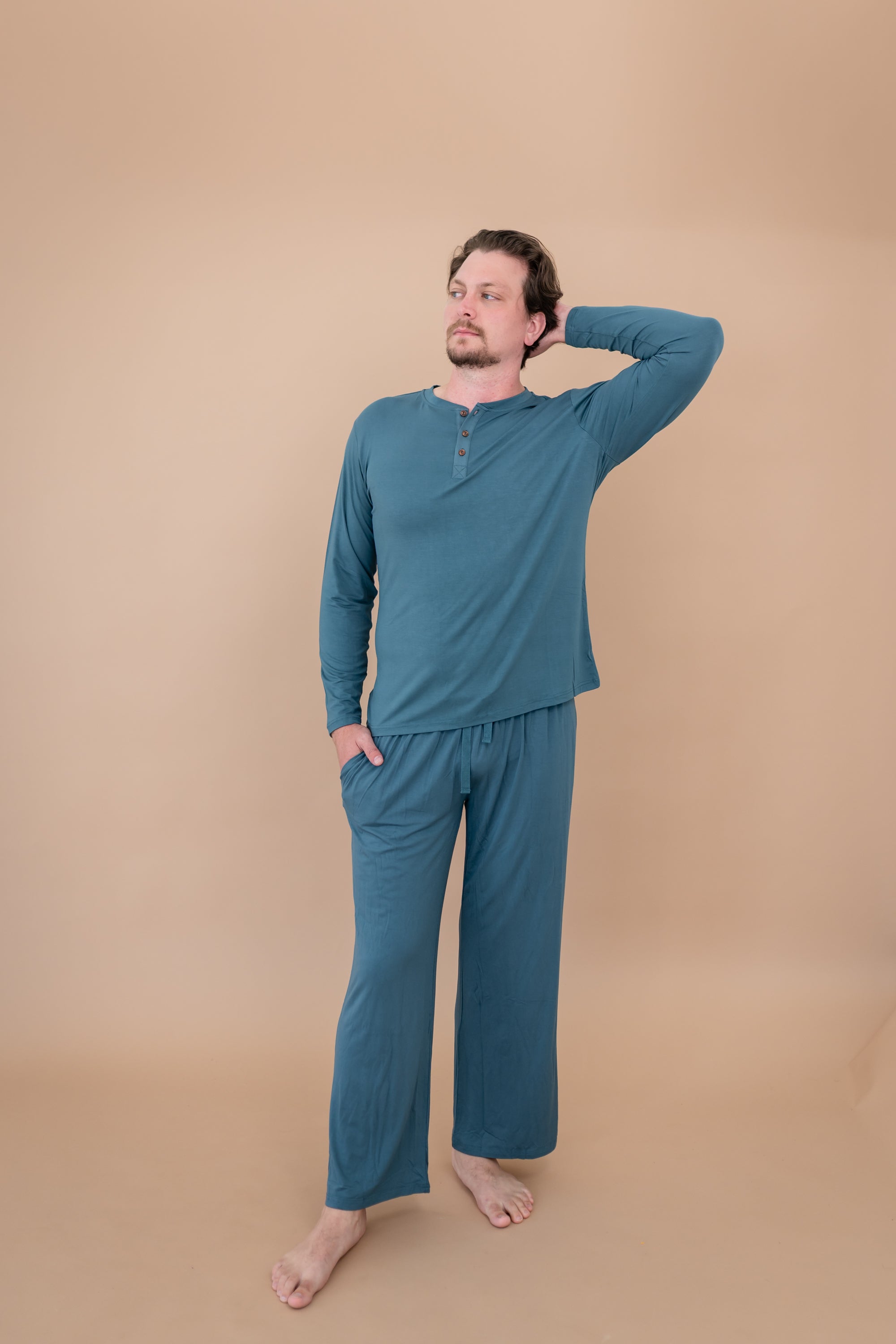 Male model with head on shoulder modeling the Men's Lounge Pants in Atlantic and matching Long Sleeve Henley Tee