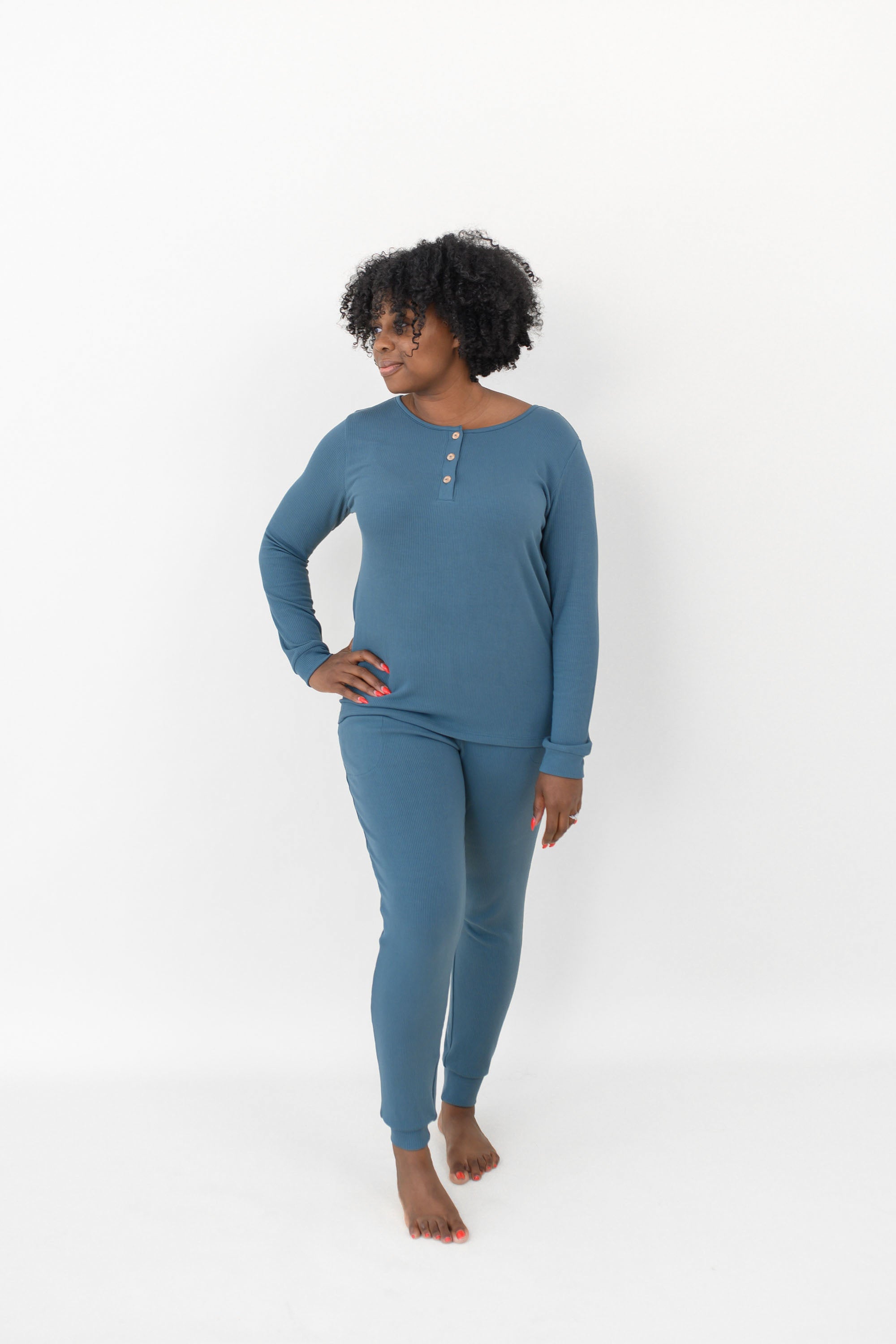 Woman looking to the side with one hand on her hip while modeling the Women’s Ribbed Henley Set in Atlantic