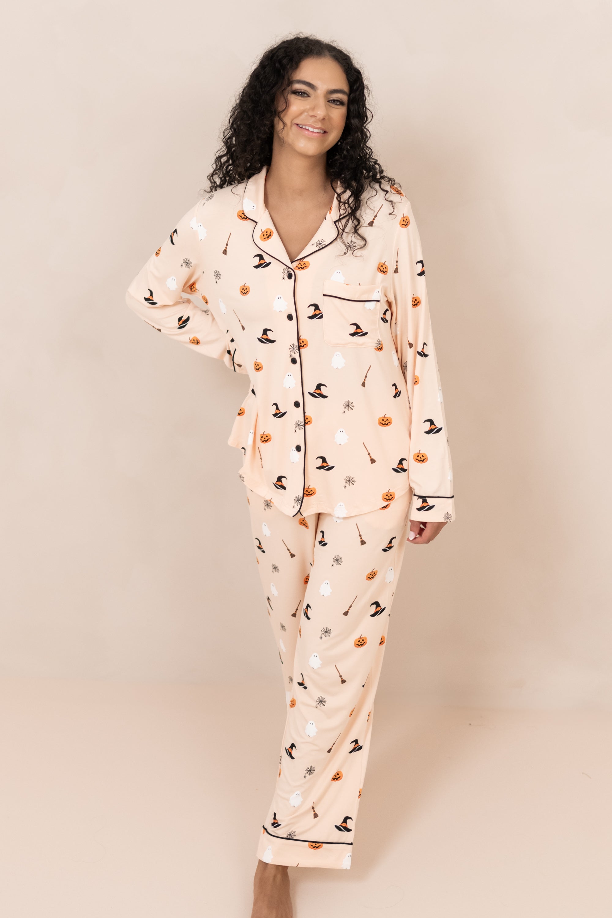 Smiling model standing with hand on her hip while wearing the Kyte Women's Long Sleeve Pajama Set in Bewitched