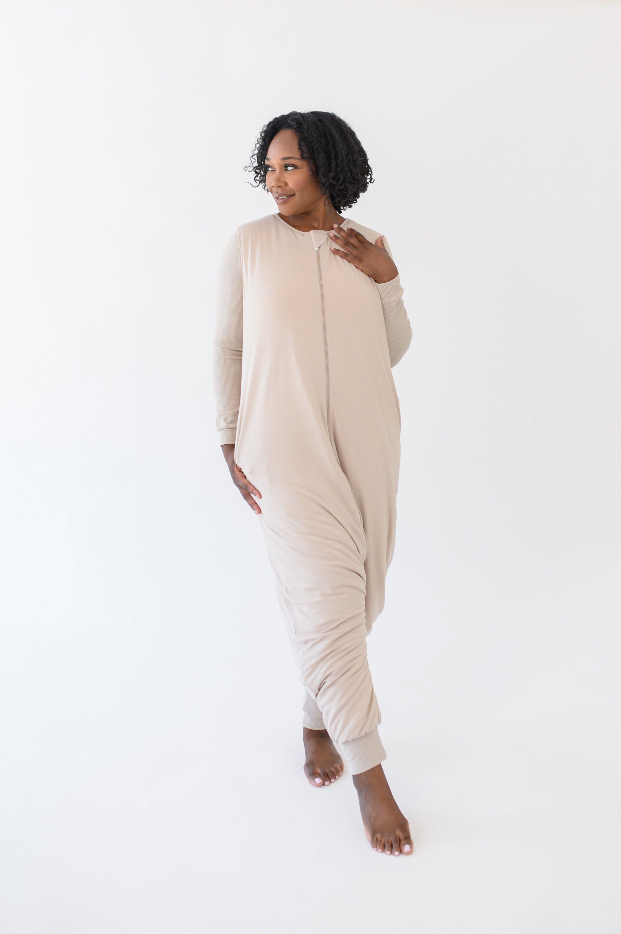 Model looking to the side while standing with one foot forward modeling the Adult Sleep Bag Walker in Bisque
