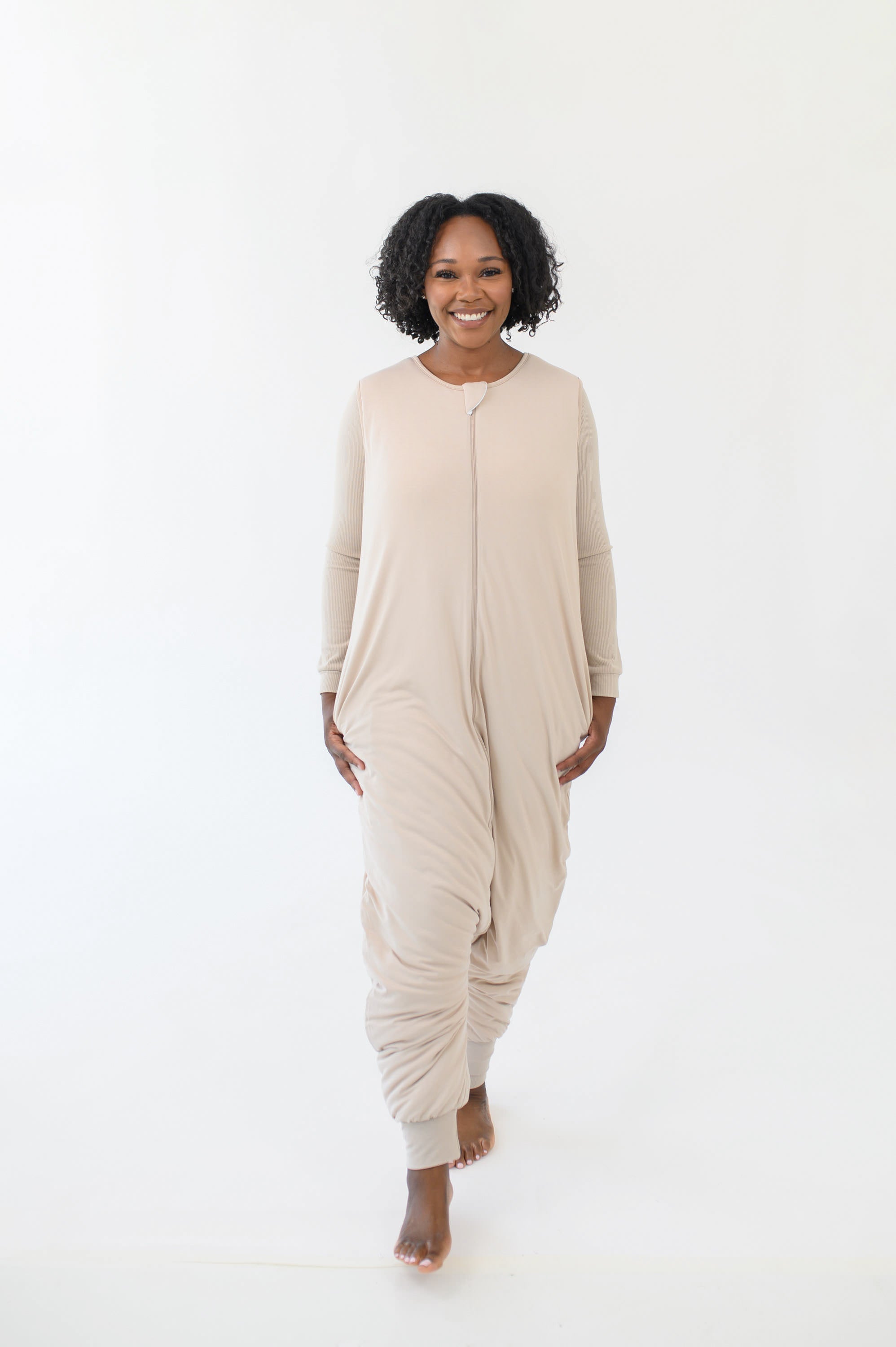 Woman modeling the Kyte Sleep Bag Walker in Bisque while standing in a white room