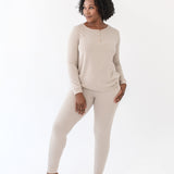 Female model standing looking off to the side wearing the Women’s Ribbed Henley Set in Bisque with one hand in the jogger pants pocket