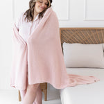 Model standing wrapped in the Chunky Knit Throw Blanket in Blush