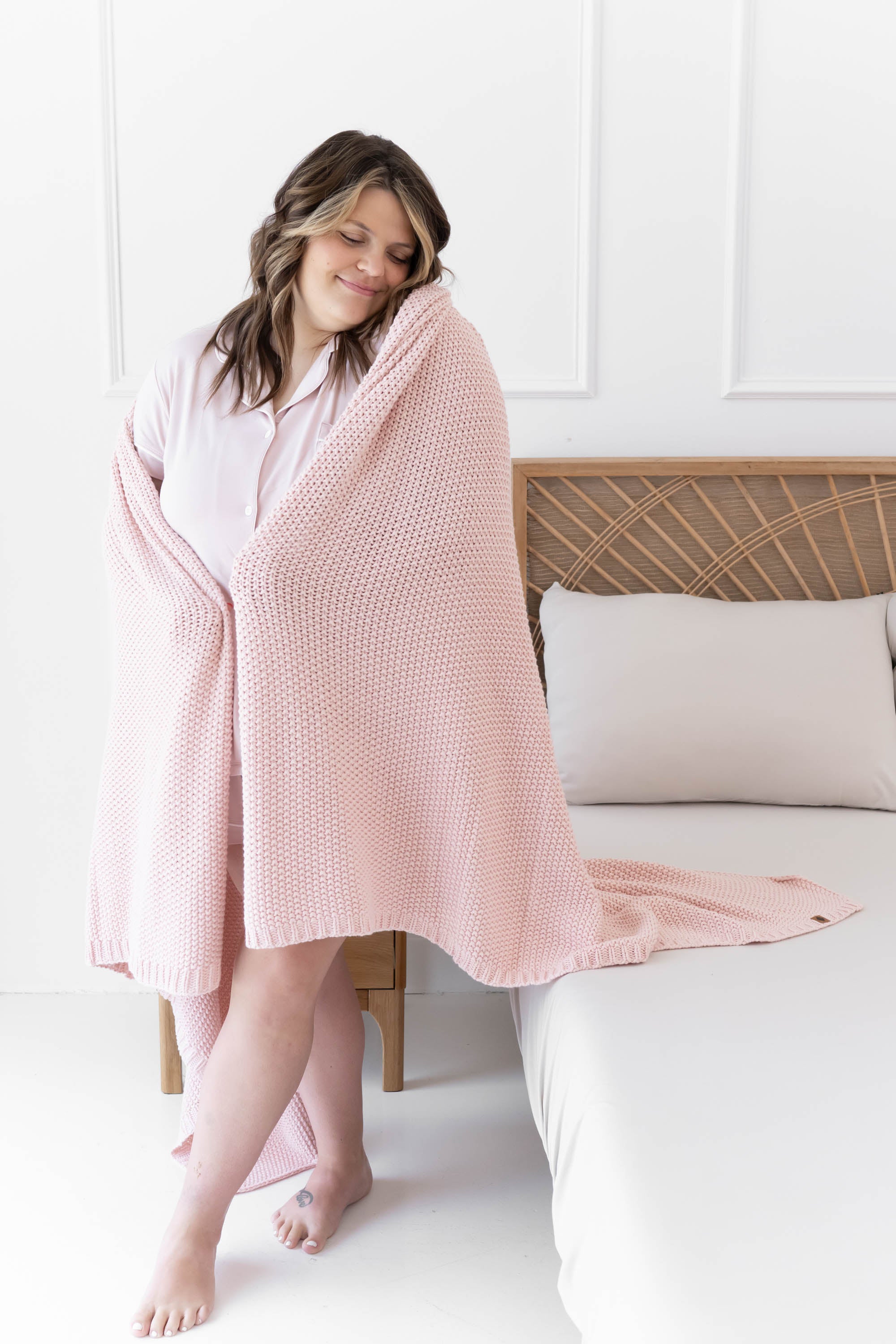 Model standing wrapped in the Chunky Knit Throw Blanket in Blush