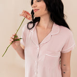 Woman modeling Women’s Short Sleeve Pajama Set in Blush with Cloud Trim while holding a flower