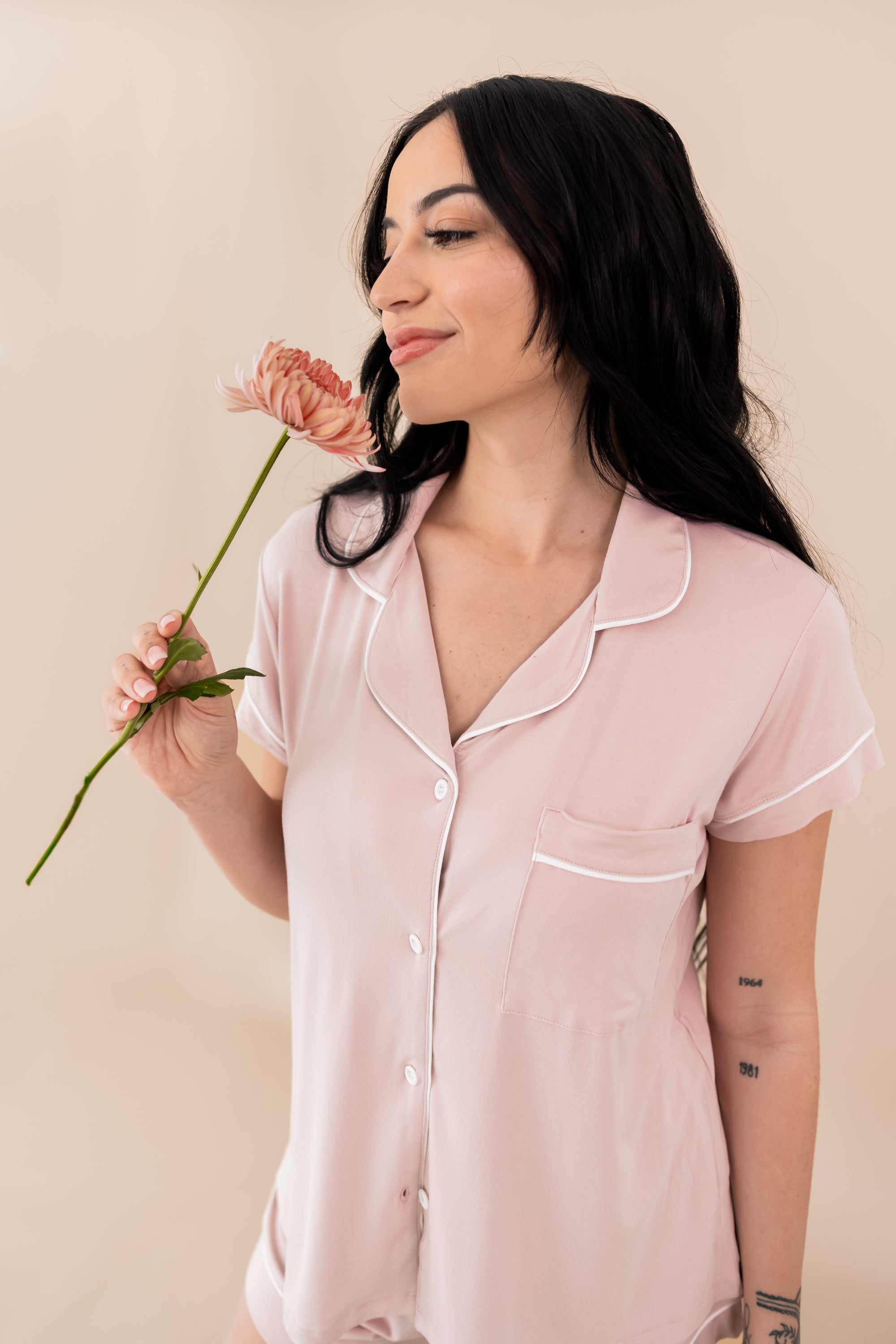 Woman modeling Women’s Short Sleeve Pajama Set in Blush with Cloud Trim while holding a flower