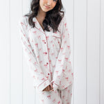 Woman modeling white long sleeve button up pajama set with pink bow print and pink piping