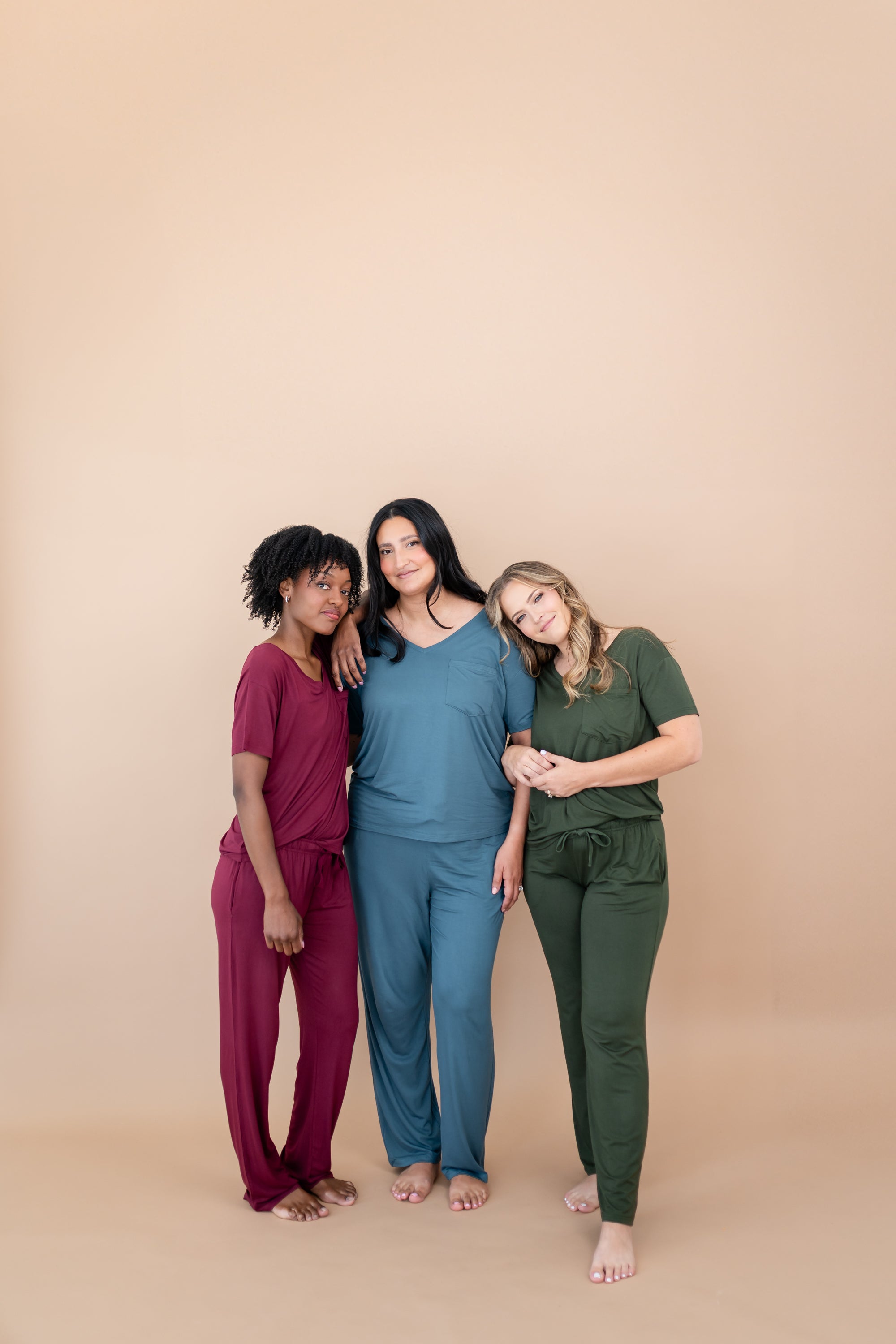 Models standing next to each other while wearing Women's V Necks in Burgundy, Atlantic and Fir and matching Lounge Pants