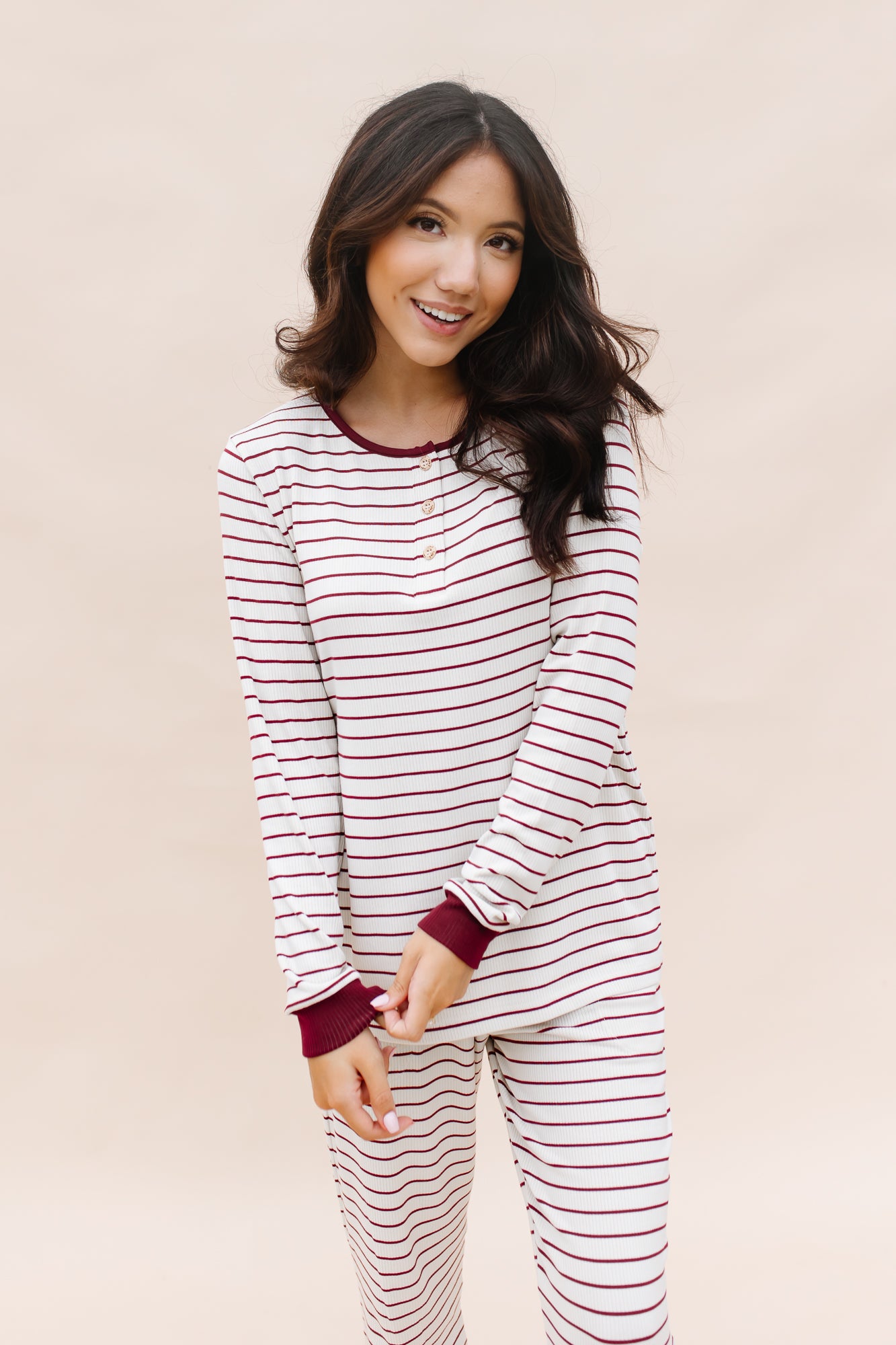 Model smiling wearing the Women's RIbbed Henley Set in Burgundy Stripe while holding one sleeve