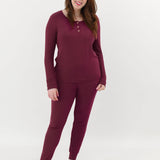 Smiling female model wearing the Women’s Ribbed Henley Set in Burgundy in front of a light colored back drop