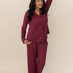 Model with hand on her head while wearing the Kyte Bamboo Long-Sleeved Women's Pajama Set in Burgundy with Burgundy Trim