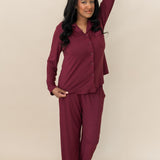 Model with hand on her head while wearing the Kyte Bamboo Long-Sleeved Women's Pajama Set in Burgundy with Burgundy Trim