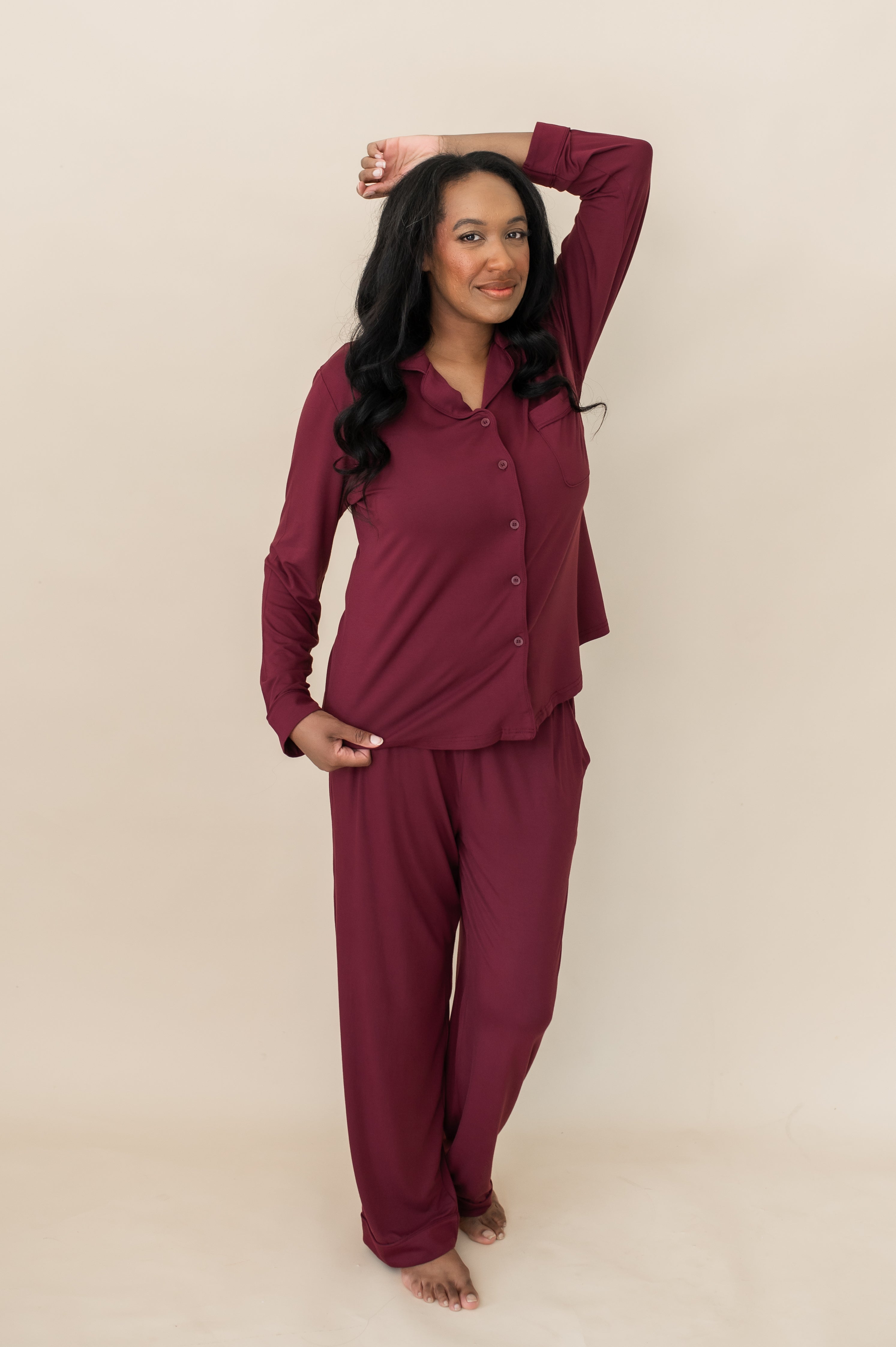 Model with hand on her head while wearing the Kyte Bamboo Long-Sleeved Women's Pajama Set in Burgundy with Burgundy Trim