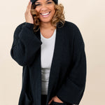 Smiling model wearing the Chunky Knit Adult Ribbed Beanie in Midnight with the Kyte Baby Leather logo visible