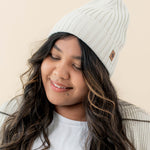Smiling model wearing the Chunky Knit Adult Ribbed Beanie in Oat