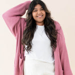 Model wearing the Chunky Knit Women's Oversized Cardigan in Apple Blossom with a white shirt and white pants