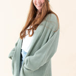 Model wearing the Thyme Chunky Knit Women's Oversized Cardigan paired with a Thyme Beanie, white shirt and light wash jeans