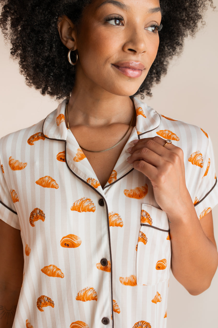Model showcasing the collar on Women's Short Sleeve Cropped Pajama Set in Croissant print with brown trim on a beige background