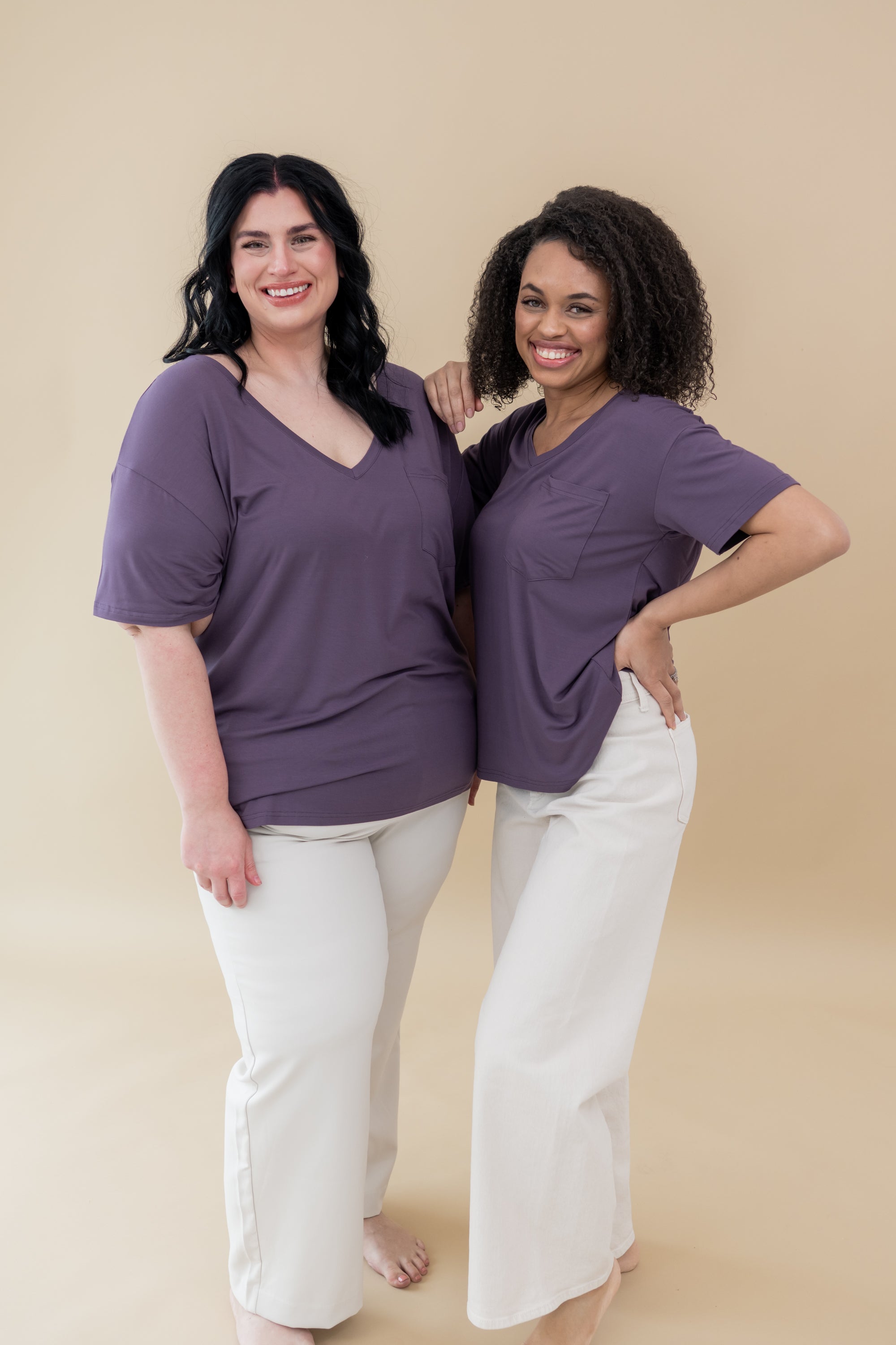 Two models both wearing the Women’s Relaxed Fit V-Neck in Currant and white jeans