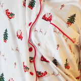 Close up of a white button up pajama top with red piping and a christmas pattern