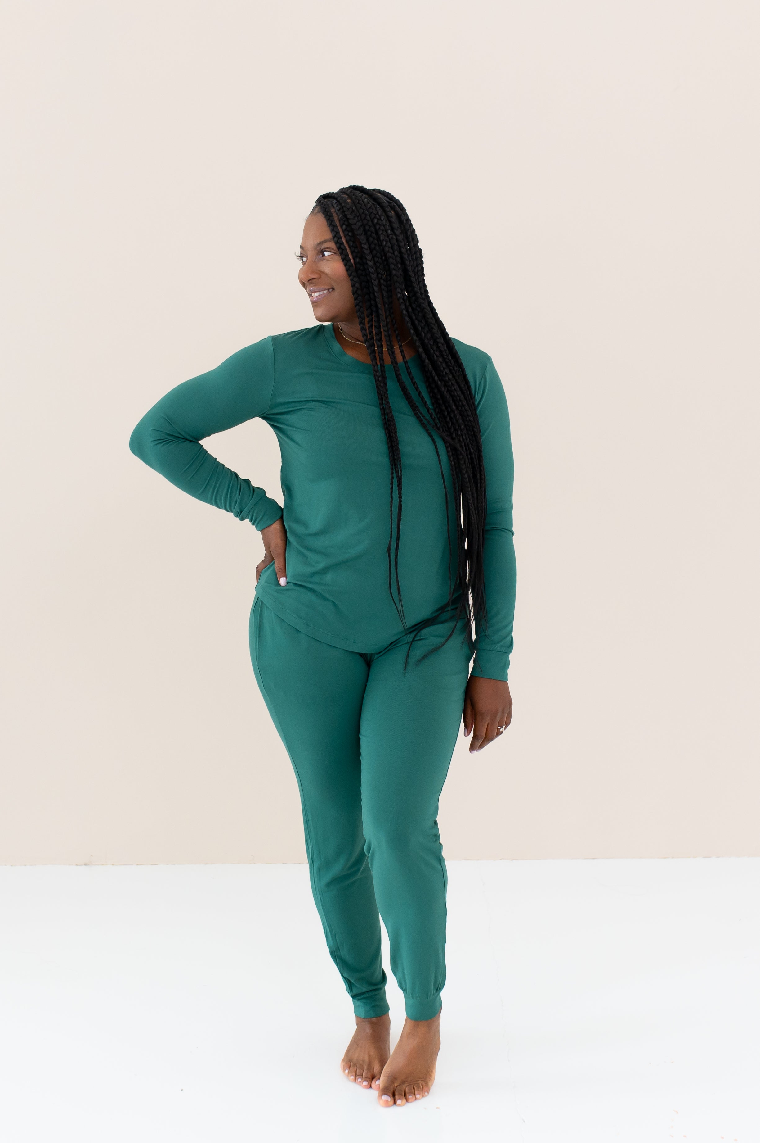 Woman modeling Women's Jogger Pajama Set in Emerald with hand on hip
looking off to the side with braided hair in front of shoulder