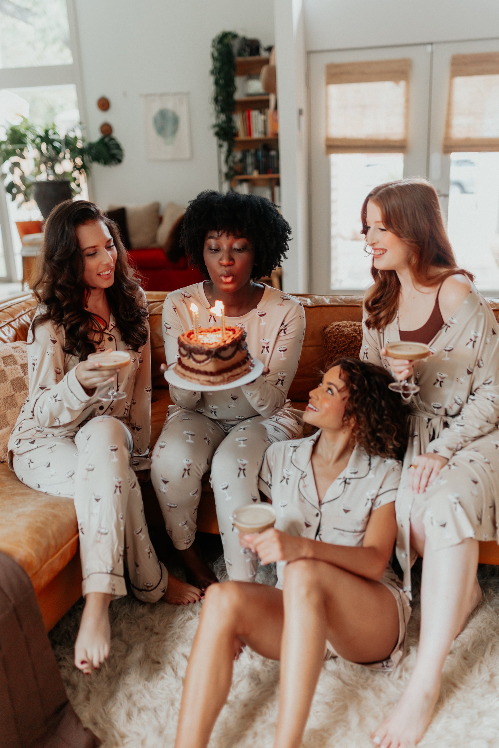A group of women sitting around a cake while modeling different styles in  Espresso Martini