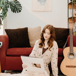 Woman sitting on the floor, next to a guitar while modeling the Women's Lounge Robe in Espresso Martini