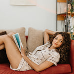 Model looking to the side while laying on a couch and modeling the Bamboo Women's Short Sleeve Pajama Set in Espresso Martini