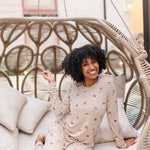 Smiling model in a rattan chair wearing the Women's Jogger Set in Espresso Martini