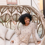 Smiling model in a rattan chair wearing the Women's Jogger Set in Espresso Martini