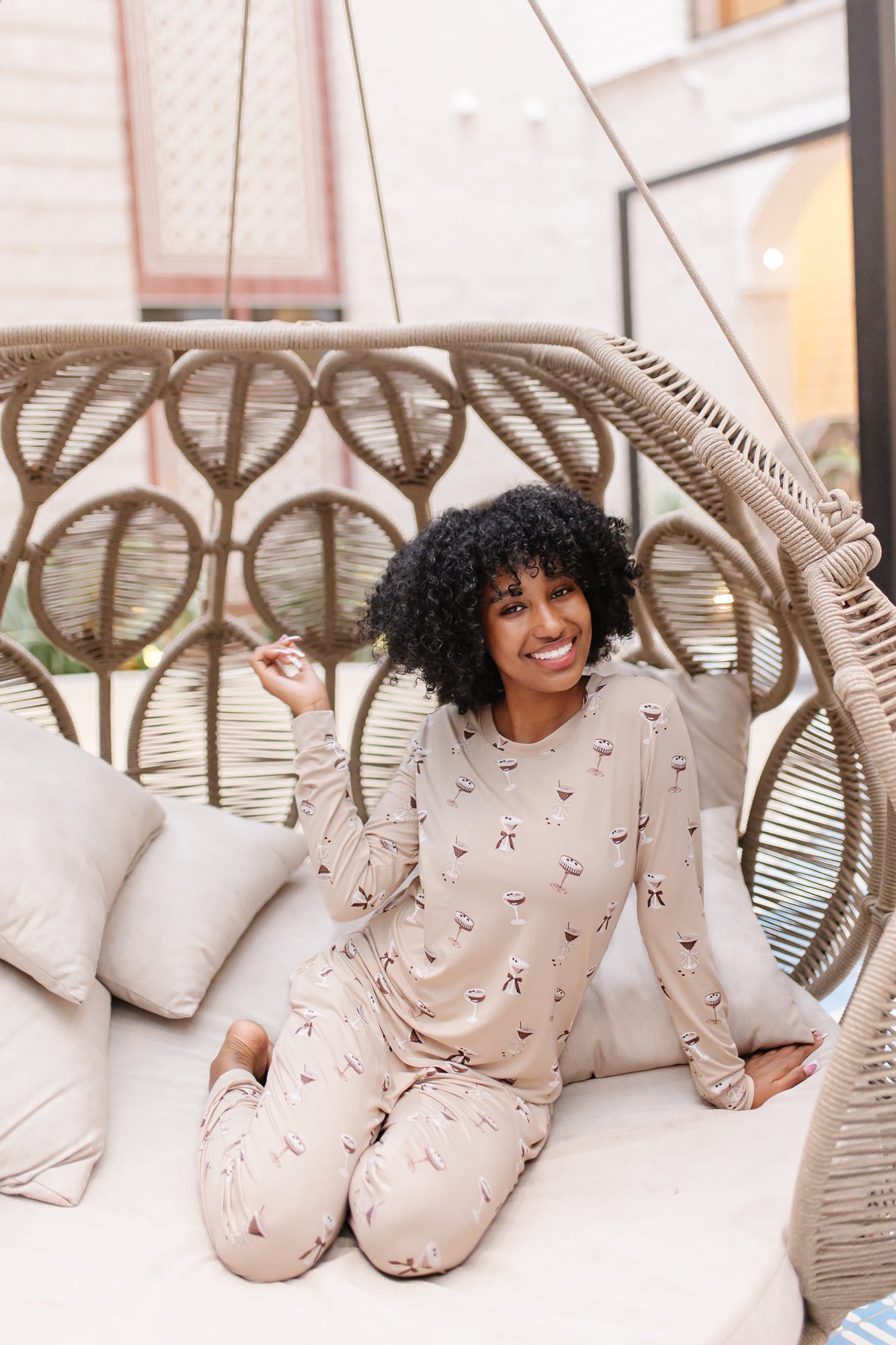 Smiling model in a rattan chair wearing the Women's Jogger Set in Espresso Martini