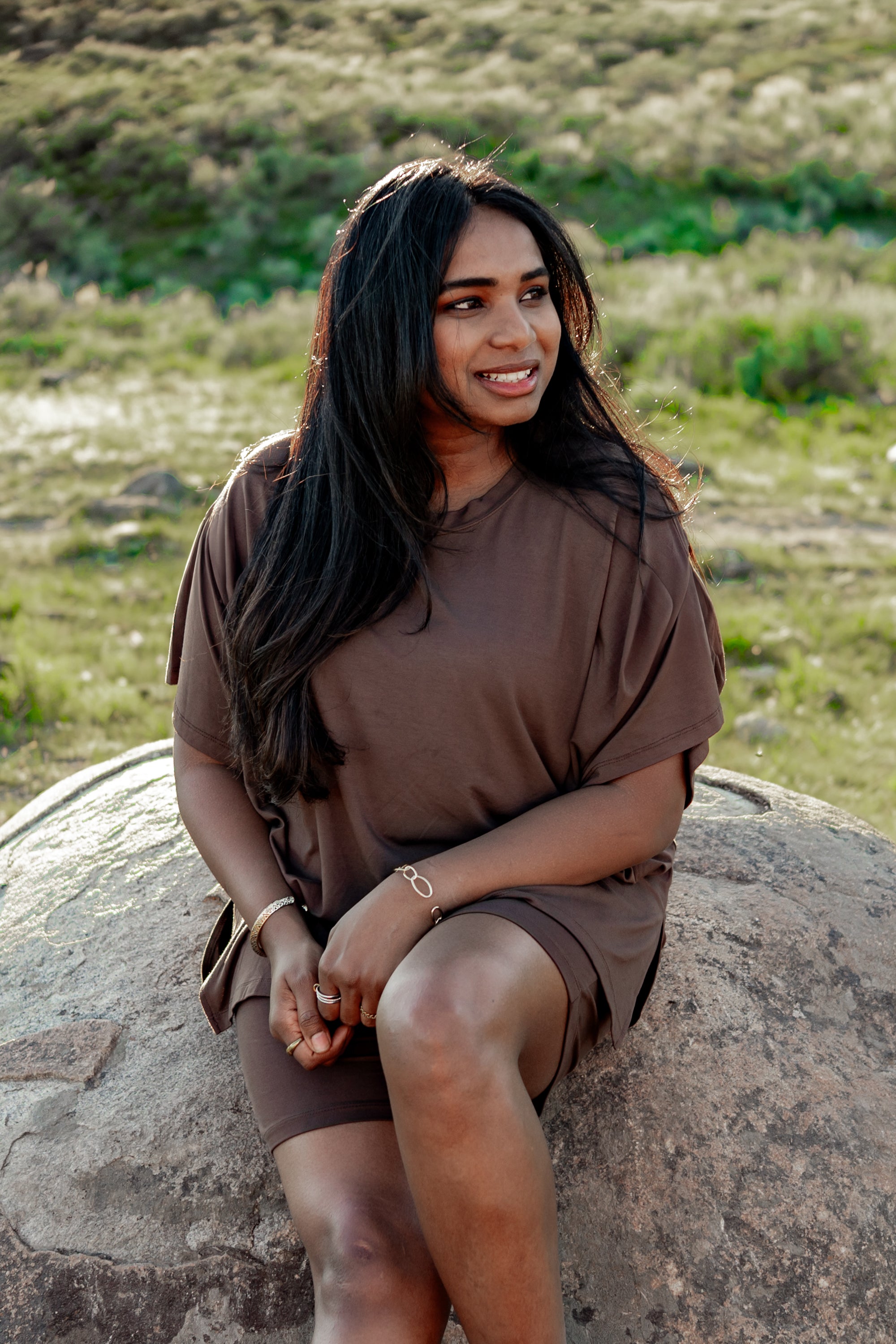 Model looking to the side wearing the Women's Biker Short Set in Espresso while sitting on a rock