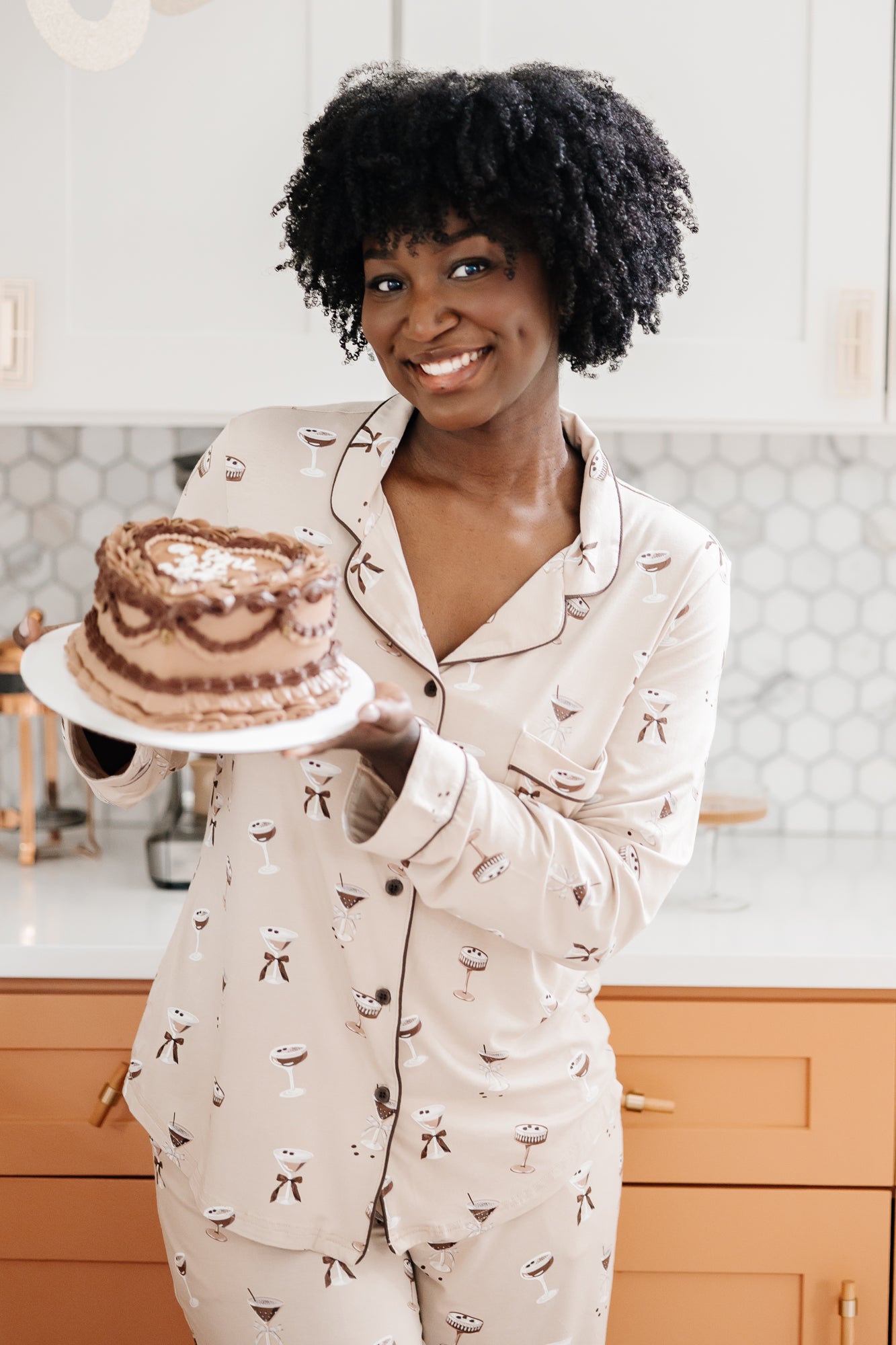 Smiling model holding a cake and modeling the Bamboo Long-Sleeved Women's Pajama Set in Espresso Martini
