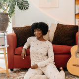 Model sitting in front of a red sofa modeling the Bamboo Women's Jogger Pajama Set in Espresso Martini