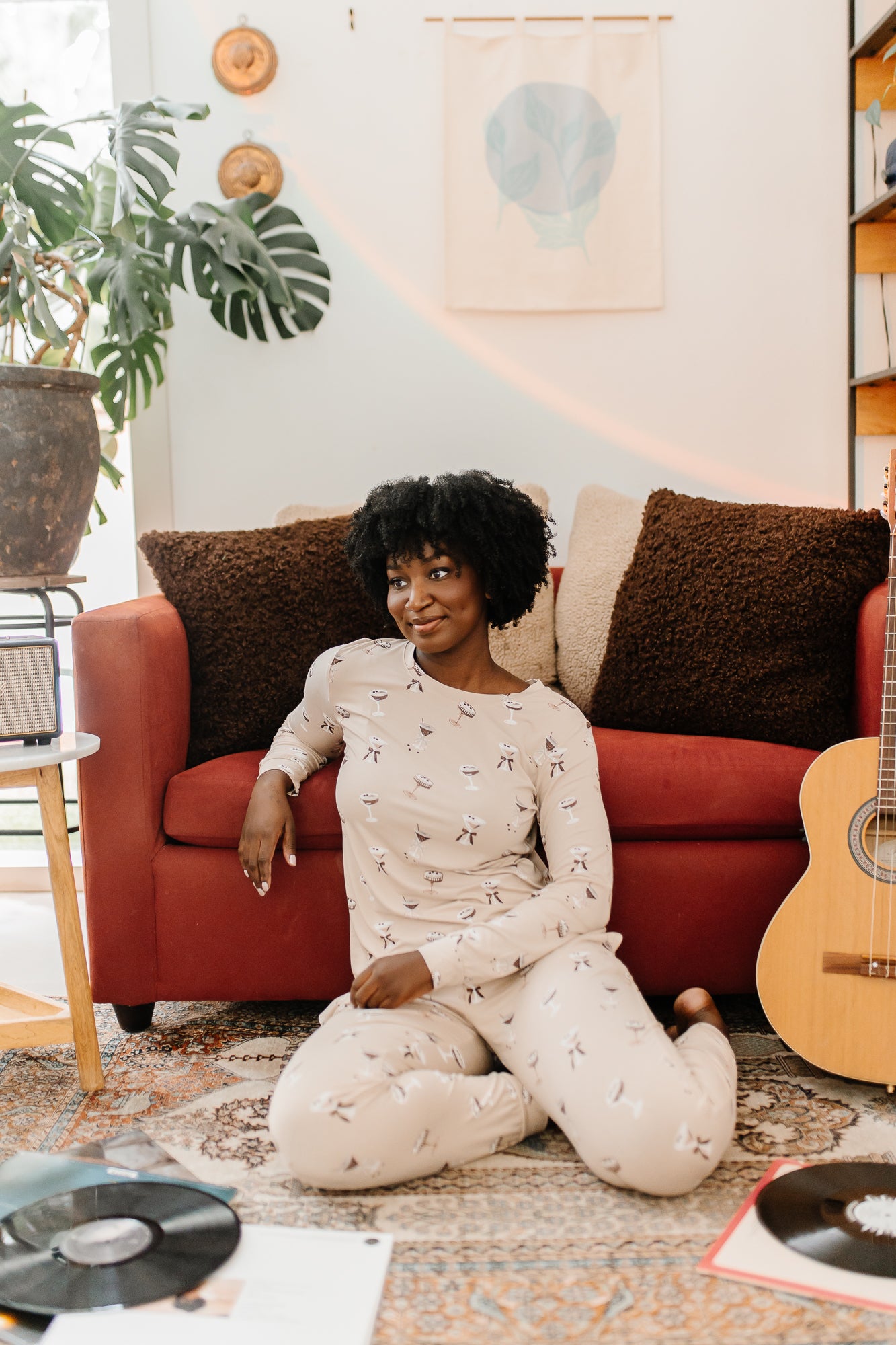 Model sitting in front of a red sofa modeling the Bamboo Women's Jogger Pajama Set in Espresso Martini