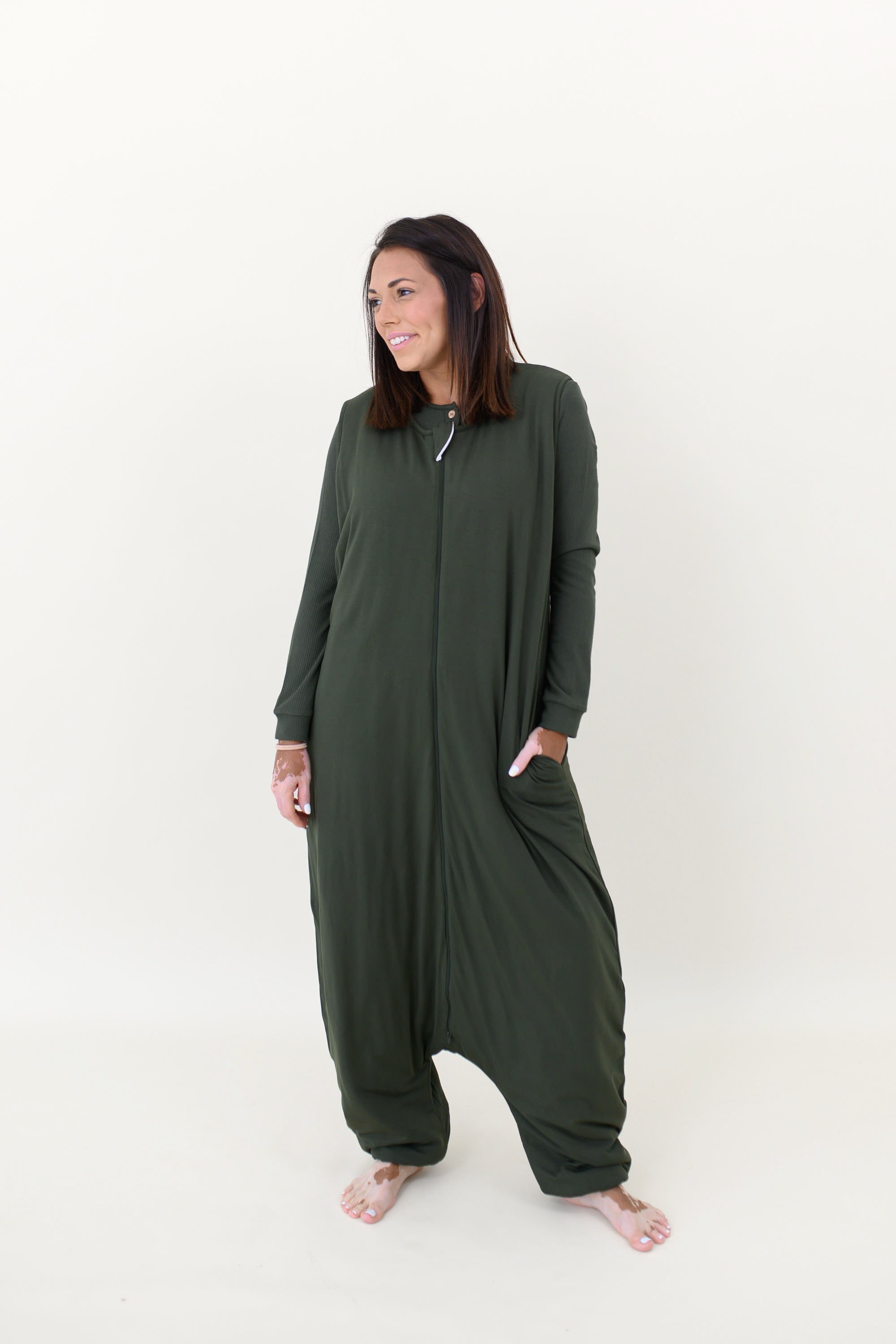 Model looking to the side while wearing the Adult Sleep Bag Walker in Fir with a hand in the pocket