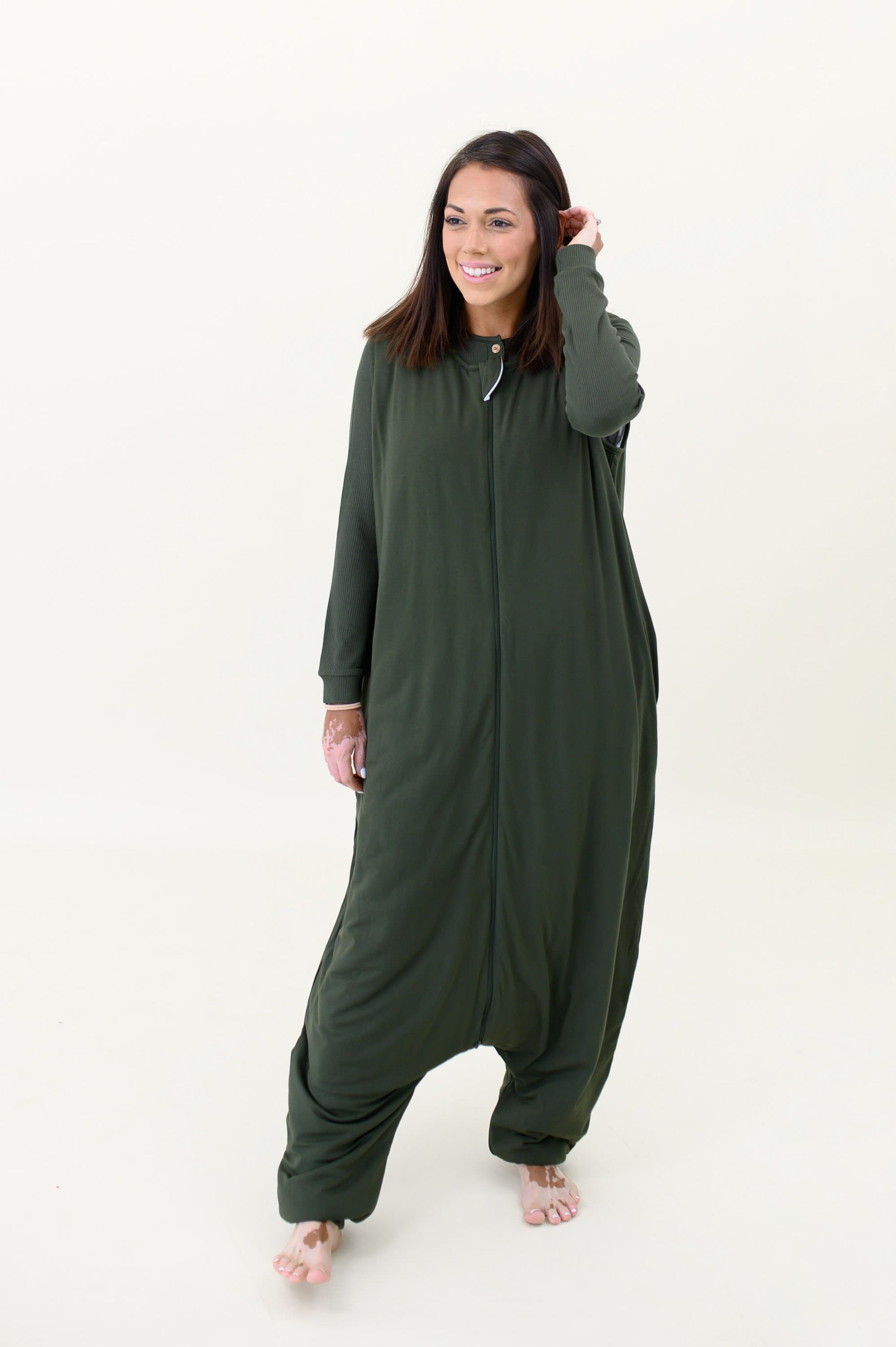 Model with hand in hair and wearing the Kyte Adult Sleep Bag Walker in Fir p