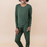 Model in a tan room wearing the Smiling model in grassy field wearing the Kyte Women's Jogger Set in Fir