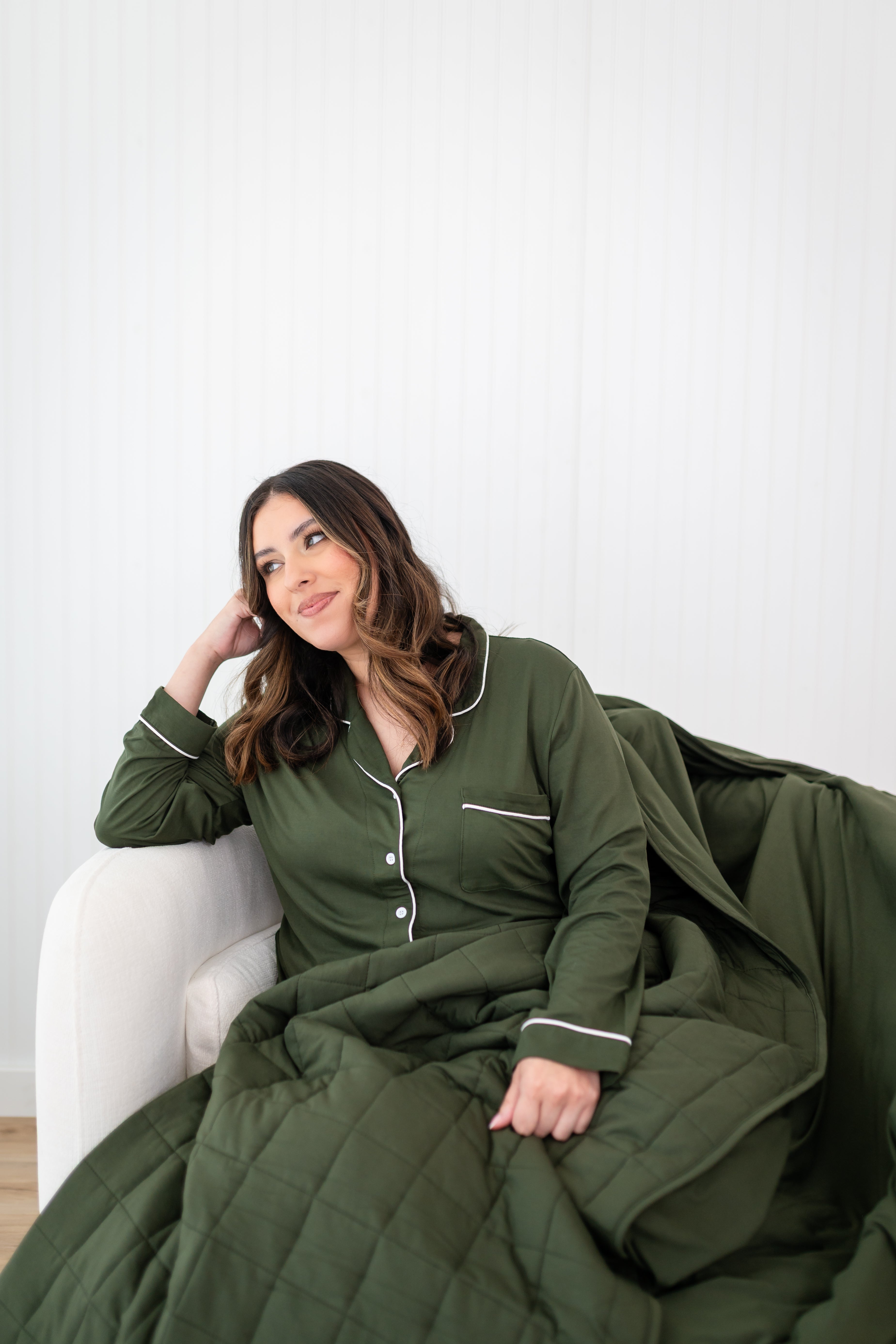 Model looking to the side while wrapped in the Quilt Blanket 2.5 and wearing Long Sleeve Pajama Set in Fir