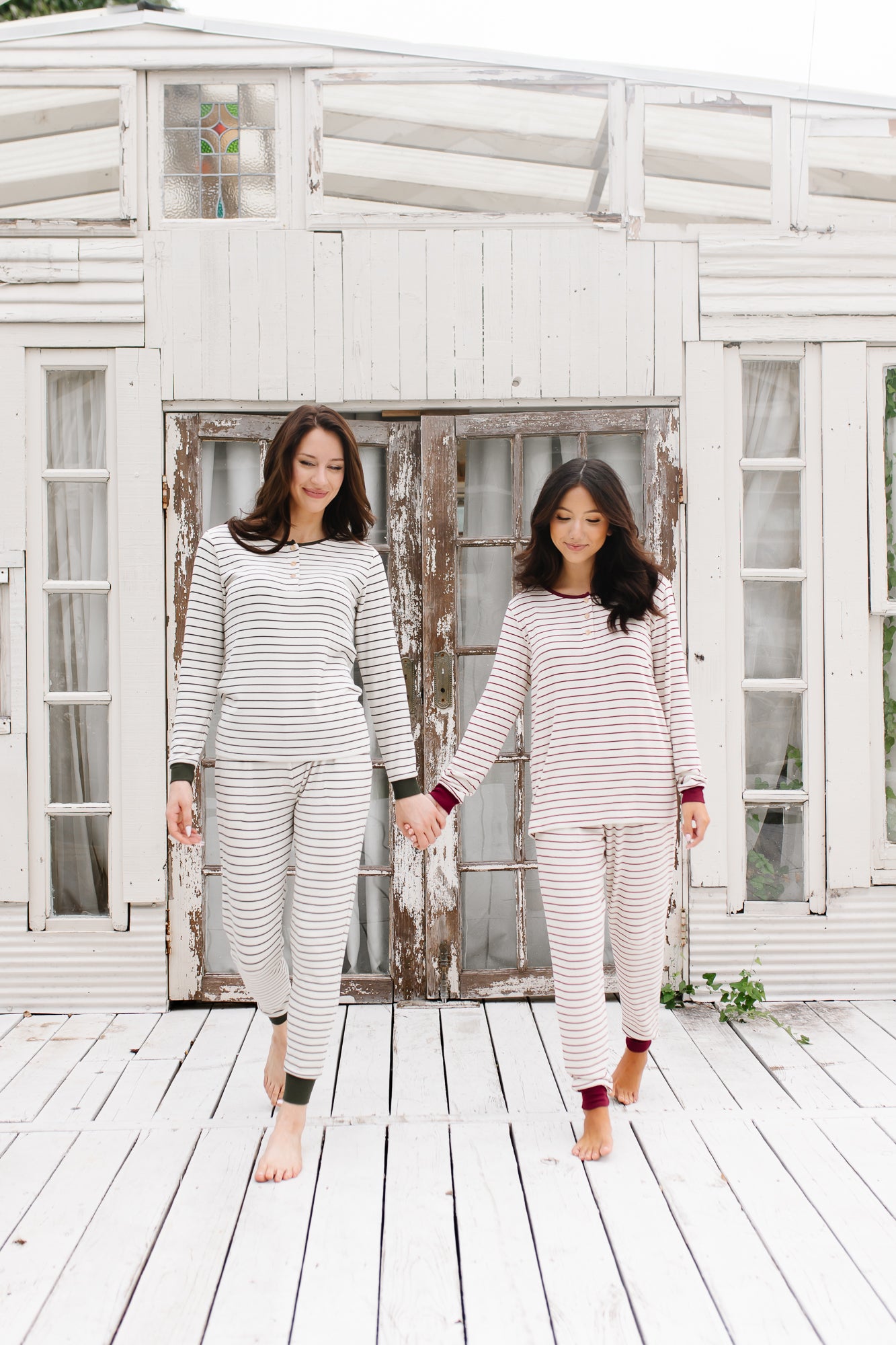 Models holding hands looking down while wearing the Women’s Ribbed Henley Set in Fir Stripe and Burgundy Stripe