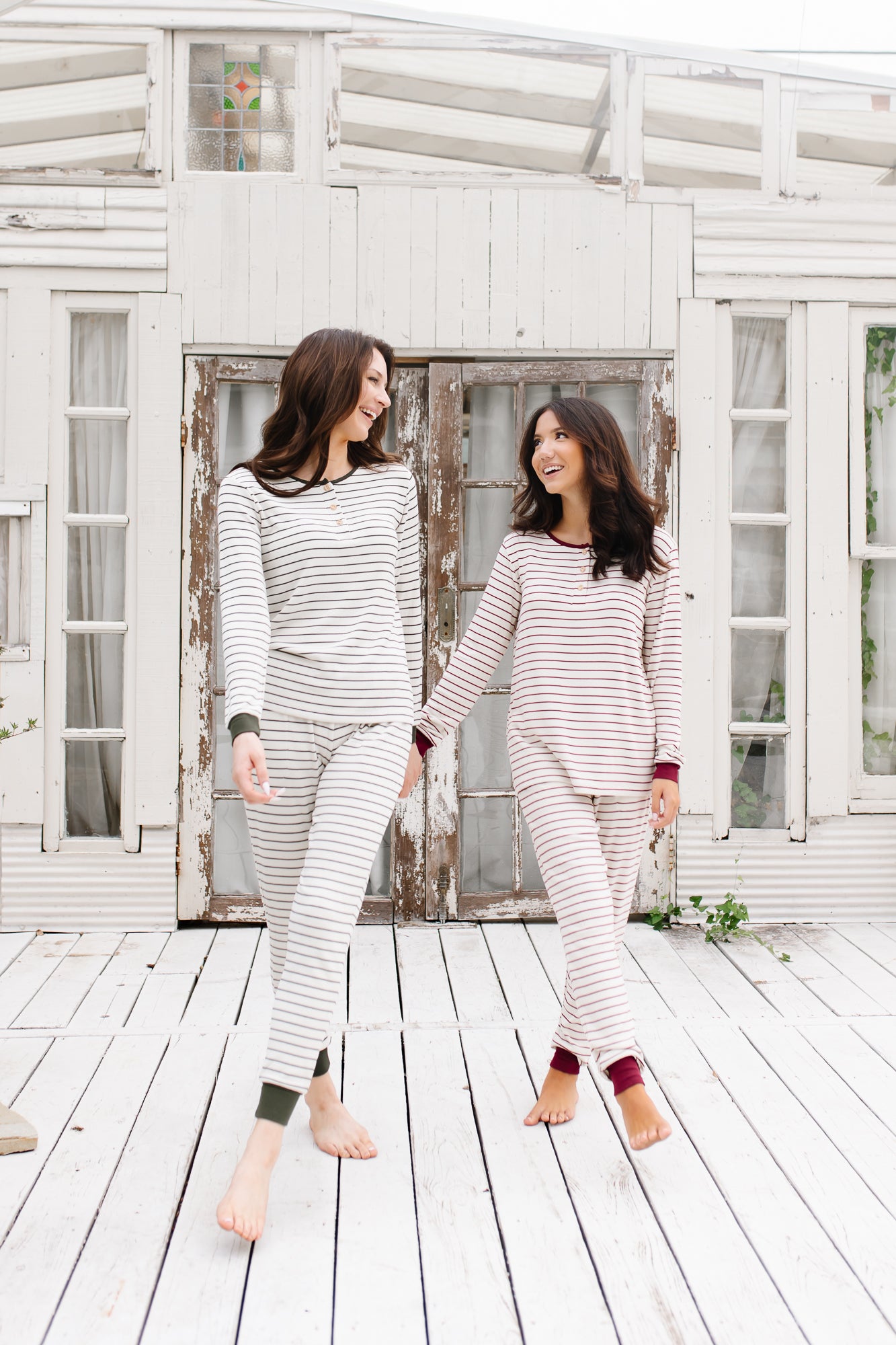 Two models holding hands and smiling at each other while wearing the Women's RIbbed Henley Set in Fir Stripe and Burgundy Stripe